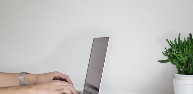 laptop leży na stole, osoba pisze na klawiaturze